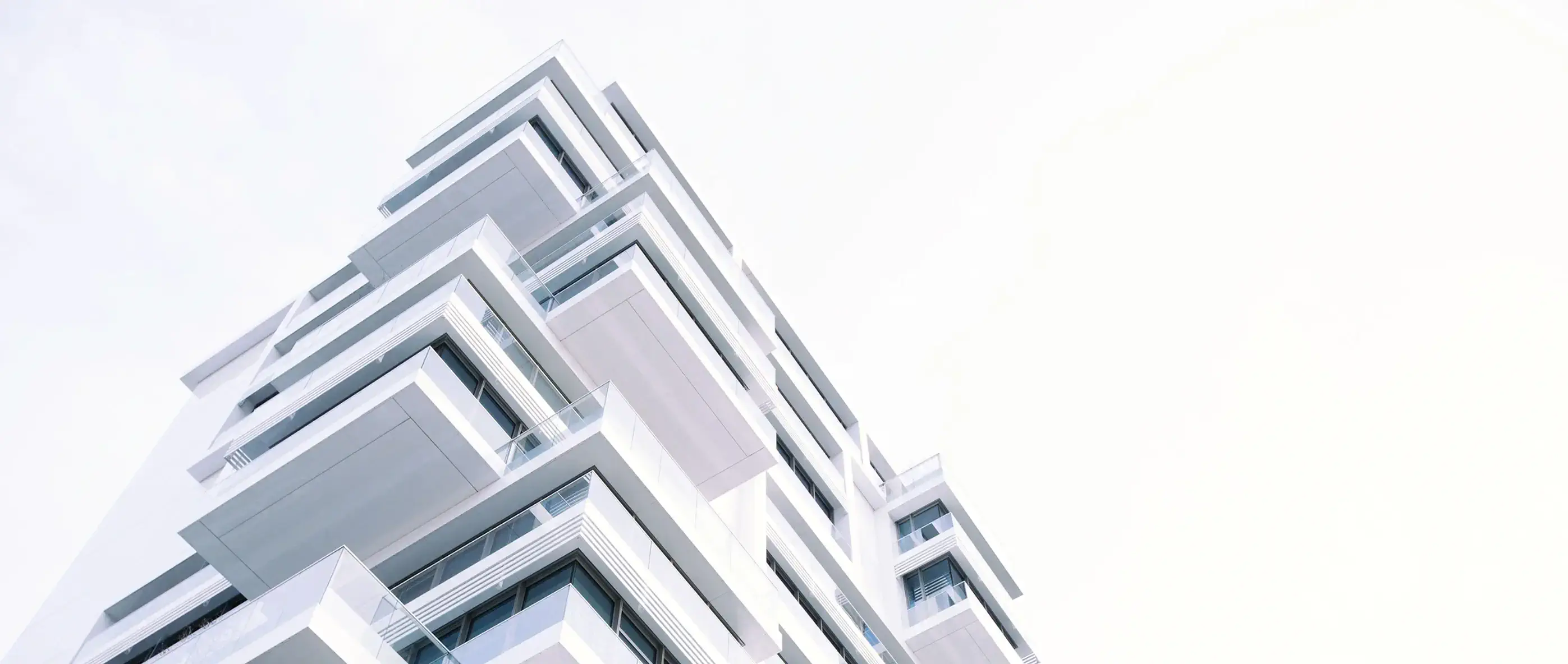 an angled image looking up at a white building with a lot of windows